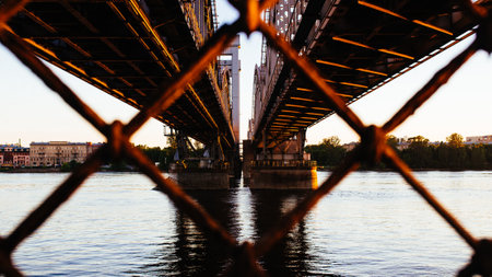 A closeup of a bridge over the river through a rusty cyclone fenceの写真素材