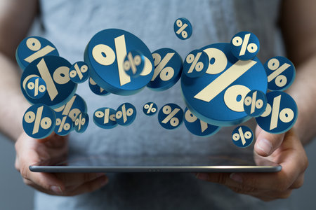 A male holding a tablet with floating blue sales iconsの写真素材
