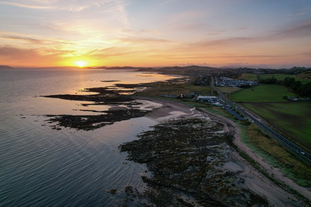 A scenic view of a calm sea and houses on the side of the coast during a beautiful sunsetの写真素材