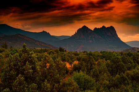 A scenic shot of a colorful sunset over the high mountains and forestの写真素材