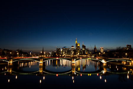 An illuminated bridge and skyscrapers of Frankfurt city at nightの写真素材