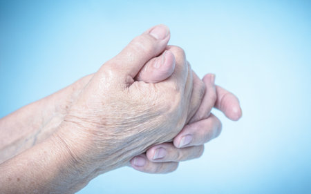 An elder female rubbing her hands with hand sanitizer on a light-blue backgroundの写真素材