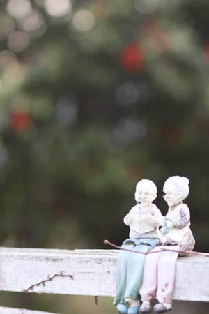 A vertical shot of dolls of an old couple on a wooden fence in a gardenの写真素材