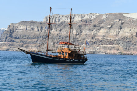 A ship with the waving flag of Greece sailing on the wavy Aegean Seaの写真素材
