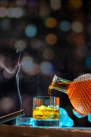 A glass of whisky and cigar on the background with bokeh effect lights