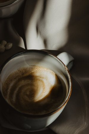 A vertical shot of a cup of foamy coffee on a fabric surfaceの写真素材