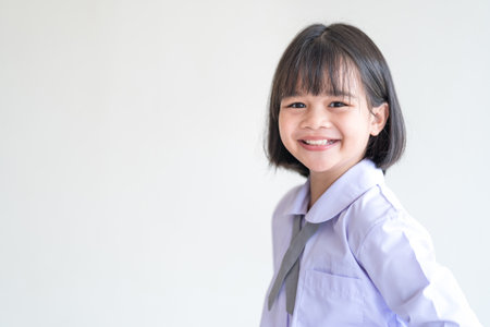 A cute smiling Southeast Asian little school girl in a uniform with short black hair and bangs