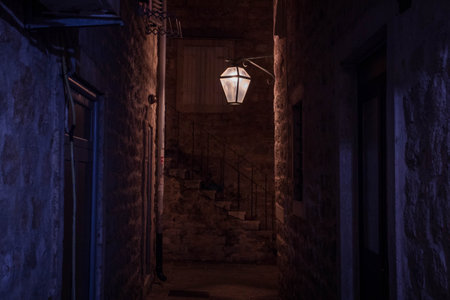 A medieval orange and dark blue old alley with a lantern at night in Budva, Montenegro