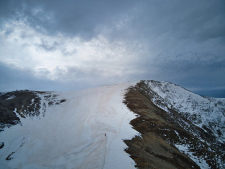 A top of a snow-capped mountain with a background of the sky.