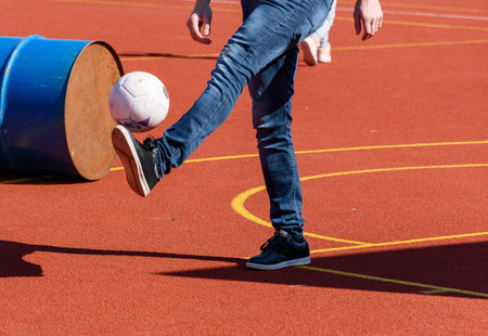 Low section photo of ma playing soccer or football on orange sports court outdoor