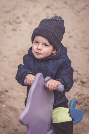 A vertical shot of a cute Caucasian (white) baby boy playing in the playground in Poland