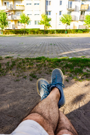 A point of view shot of hairy man's legs resting in the parkの写真素材
