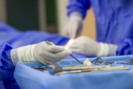 A selective focus on a hand of a nurse grabbing a tool to give it to the surgeon during the operationの写真素材