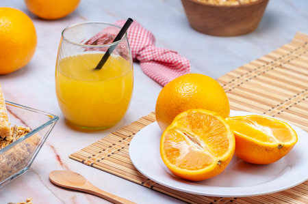 A closeup shot of fresh orange juice in the glass with a straw and oranges on the tableの写真素材