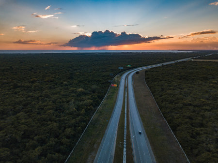 A landscape of roads surrounded by forests under a blue cloudy sky during a beautiful sunriseの写真素材
