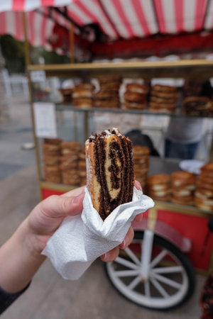 A vertical shot of a female hand holding a piece of pastry outdoors