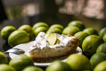 A soft focus of a slice of delicious key lime pie surrounded by fresh key limes