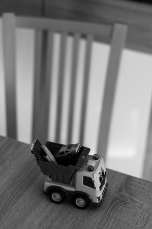 A vertical shot of a plastic toy lory on a table in grayscale