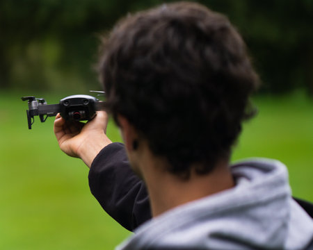 A selective focus shot of a brunette male with a drone in his hand