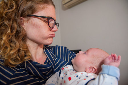 A closeup of a happy mother playing with her cute little newborn baby