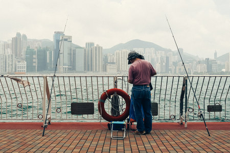 A fisherman standing on the bridge fishing in the South China Seaの写真素材