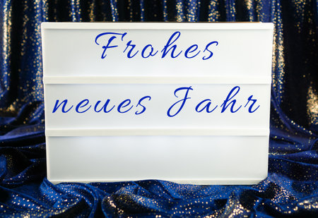 A light box with the German words for happy new year, blue and sparkling curtain in the backgroundの写真素材