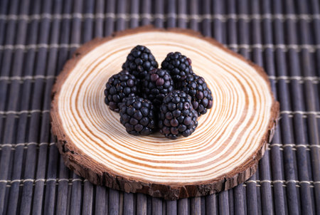 A closeup shot of blackberries beautifully set on the wooden circle-forest fruit conceptの写真素材