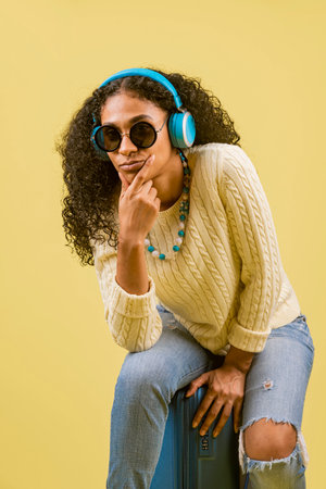A young Hispanic female enjoying music on her headphones on a yellow background