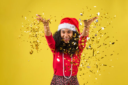 A cute Hispanic woman with a Christmas dress on a yellow backgroundの写真素材