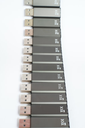 Vertical close up of black USB sticks laying in a row with white background. Selective focus macro...
