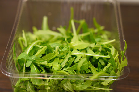 A closeup of delicious fresh arugula in a plastic container with a blurry backgroundの写真素材