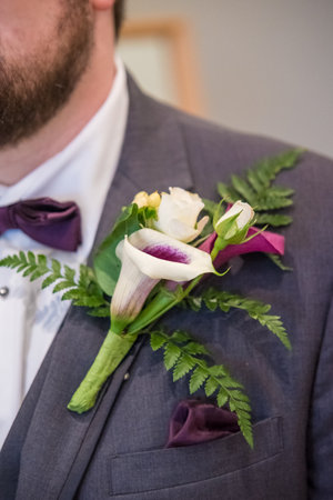 A vertical close up shot of handmade bridal flower brooch on groom suit.の写真素材