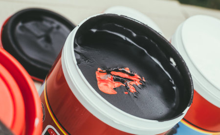 A container with black paint and a little red paintの写真素材
