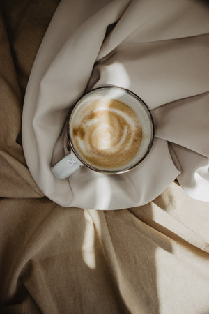 A vertical shot of a cup of foamy coffee on a fabric surfaceの写真素材