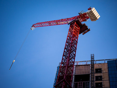 A red crane beside a building against a blue sky backdrop in Calgary, Albertaの写真素材