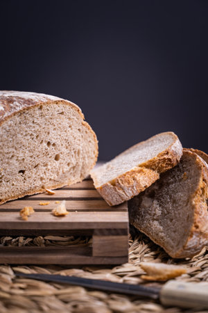 A vertical shot of rustic, village bread, cut in slices on the wooden board
