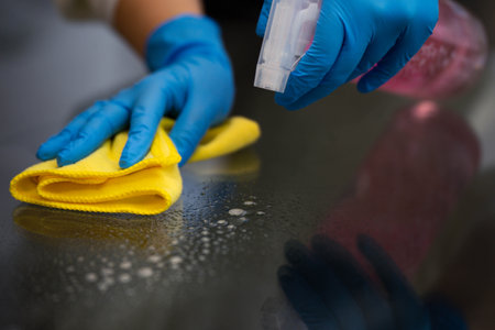 Woman cleaning a glass table with a spray and a microfiber cloth