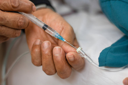 A closeup on the hands of a doctor injecting medication to a tube attached to a patientの写真素材