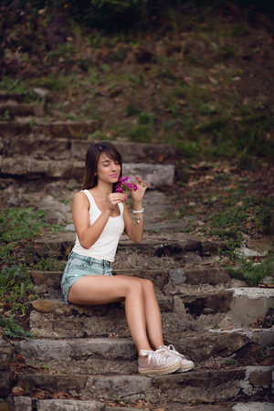 A Shallow focus of a caucasian female with a white t-shirt posing in the parkの写真素材
