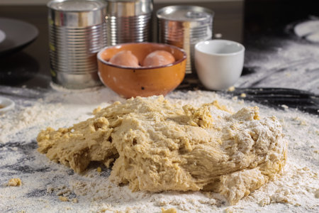 A closeup of newly made dough on top of flour with eggs in the backgroundの写真素材