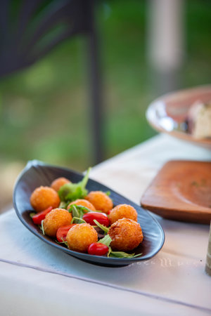 Vertical shooting of a delicious platter with fried cheese croquettes in an impressive restaurant in...