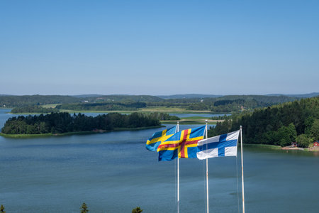 A beautiful view of Aland Islands with the flags of Aland Islands, Sweden and Finland under a blue skyの写真素材