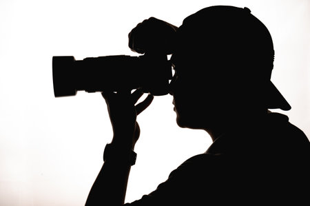 The silhouette of a photographer against a white backgrの写真素材