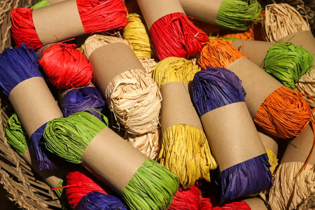 A closeup shot of many colorful rolls of raffia yarn in a basketの写真素材
