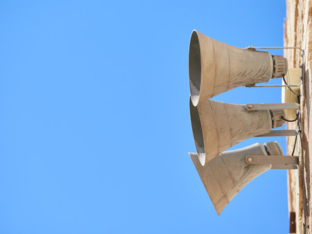 The low angle shot of three loudspeakers attached on a wall against a clear skyの写真素材