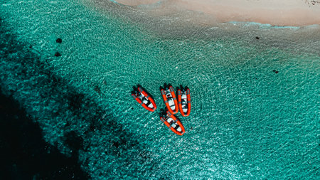 An aerial shot of boats on the sea surrounded by a beach under the sunlight