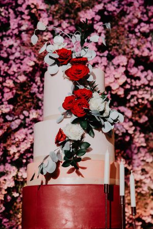 A wedding cake decorated with red roses