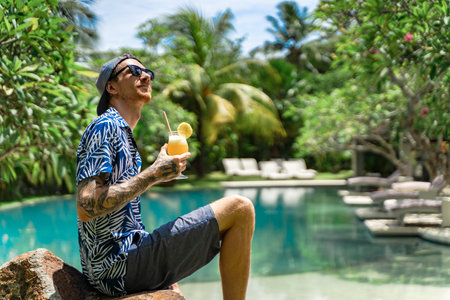 A vertical shot of Caucasian male drinking cocktails near the pool in Indonesia