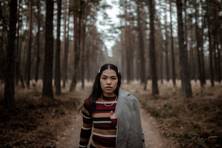 A young Hispanic woman wearing an elegant stylish outfit walking towards the camera in the forest