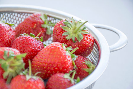 A closeup shot of freshly washed strawberries in a mesh strainer